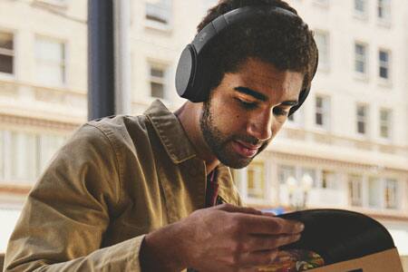Man wearing headphones looking at record album
