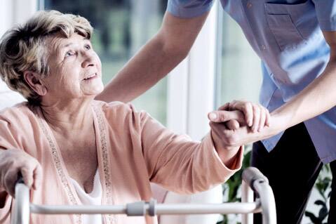 Woman with walker holding worker's hand.