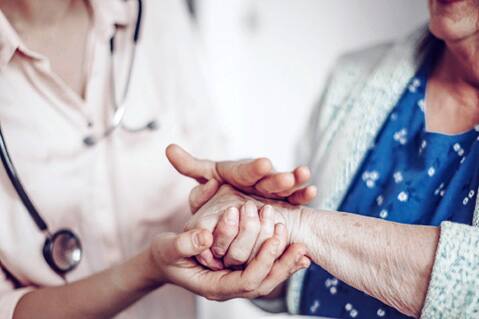 Healthcare provider holding patient's hand.