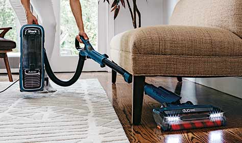 Woman vacuuming under couch