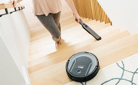 Person cleaning stairs, while robot cleans the floor