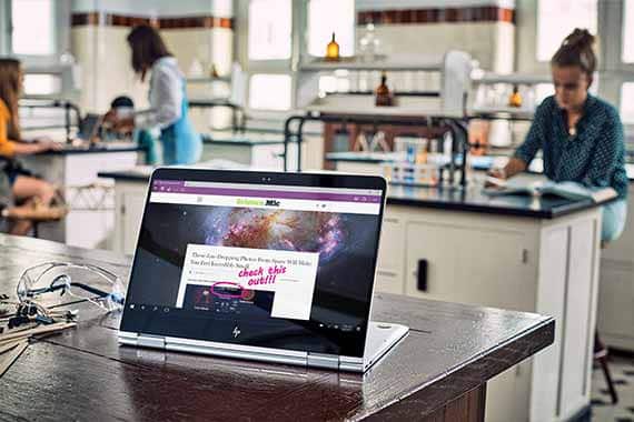 2-in-1 laptop showing science article with handwritten note on screen