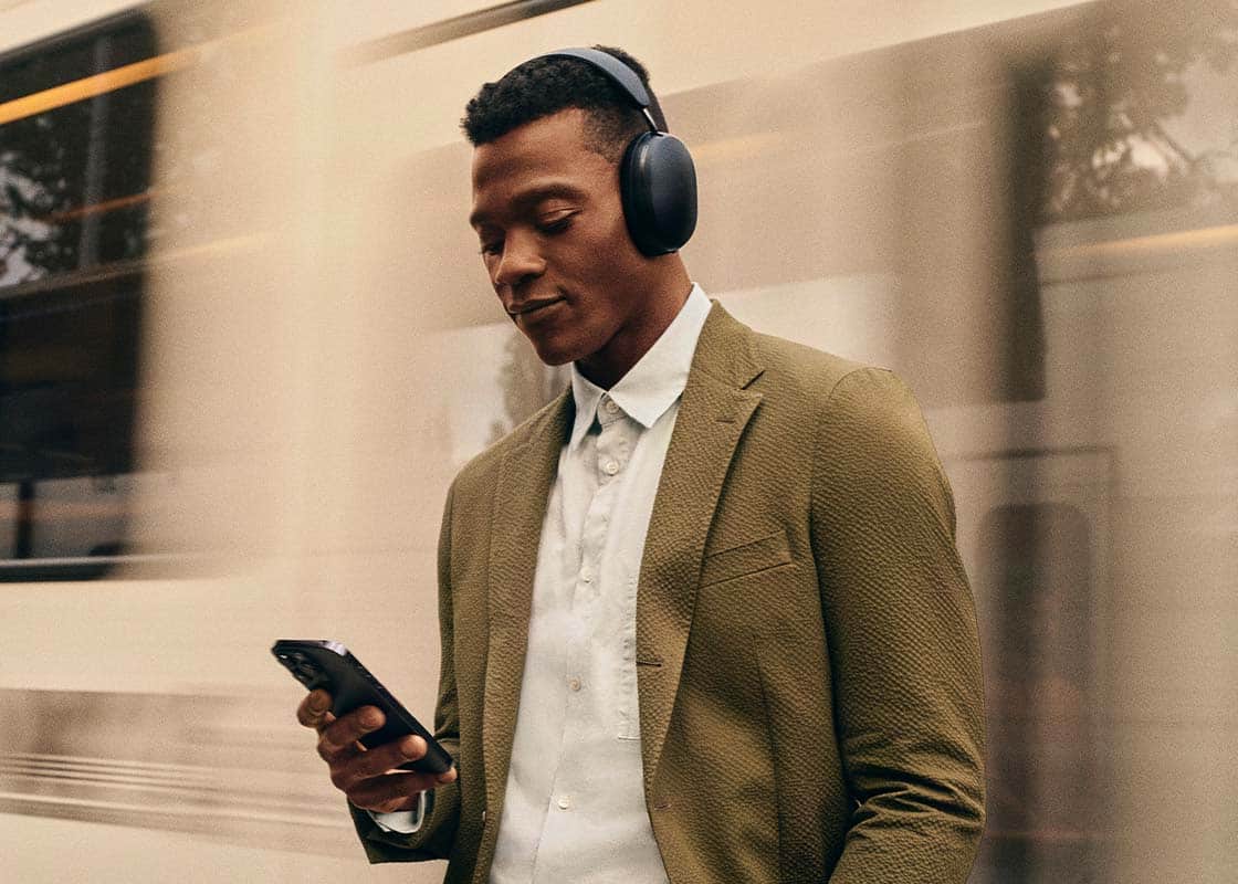 Person wearing Sonos Ace Headphones and looking at phone.