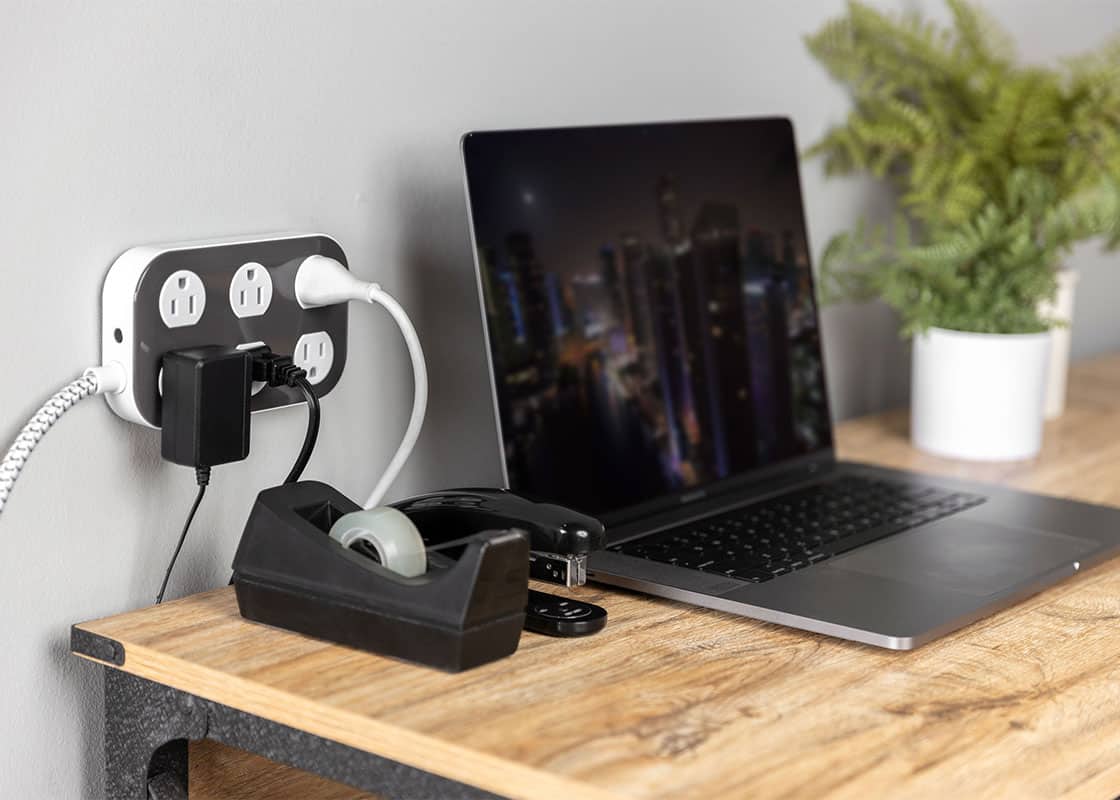 Philips surge protector on wall next to laptop.	