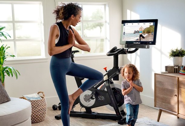 Woman exercising with child in front of exercise bike