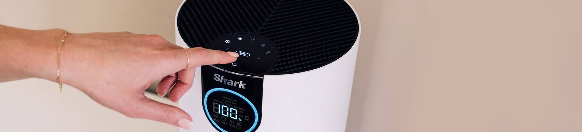 Person’s finger pushing button on air purifier