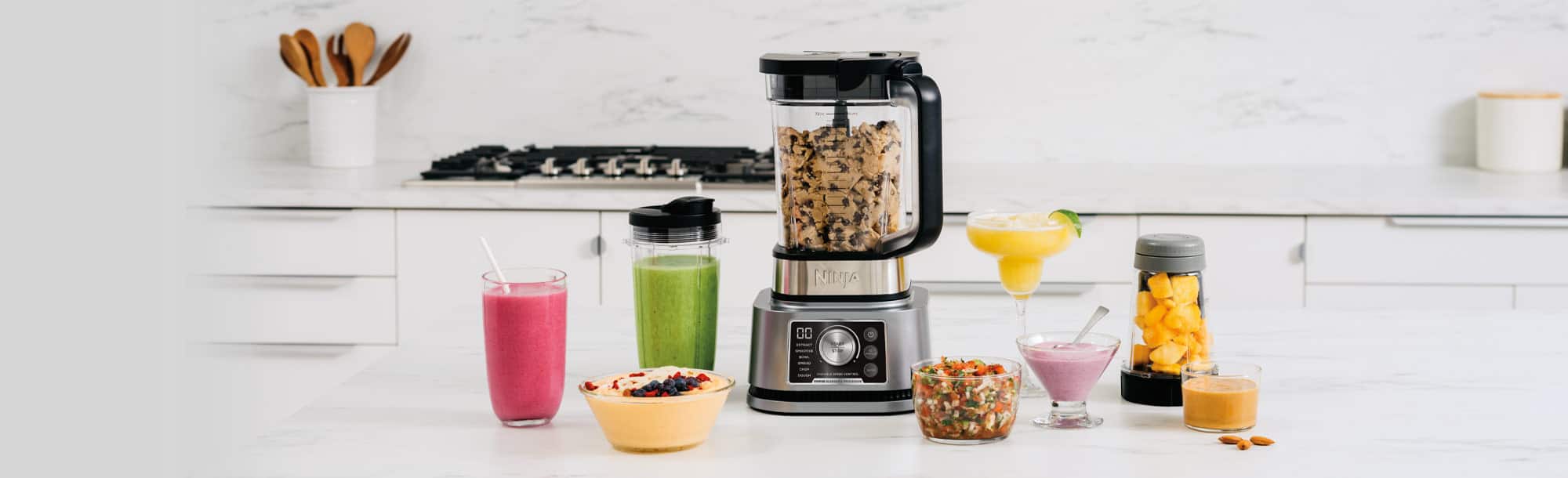 Blender on countertop with blended food and beverages