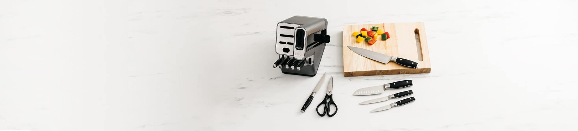 Cutlery set with knifes on countertop and hopped peppers on cutting board