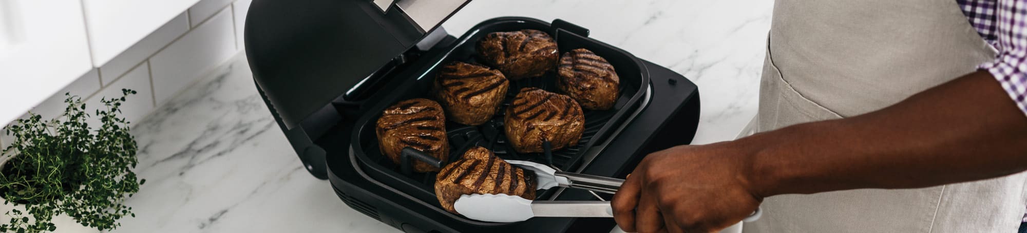 Person cooking meat on indoor grill