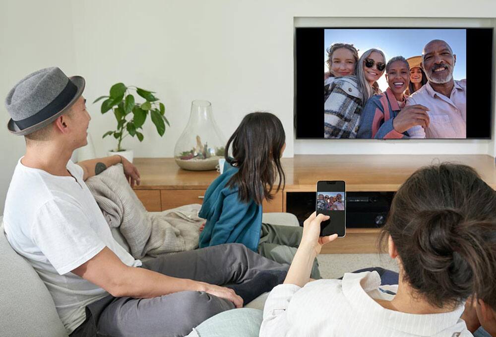 Person displaying a photo from a phone to a TV
