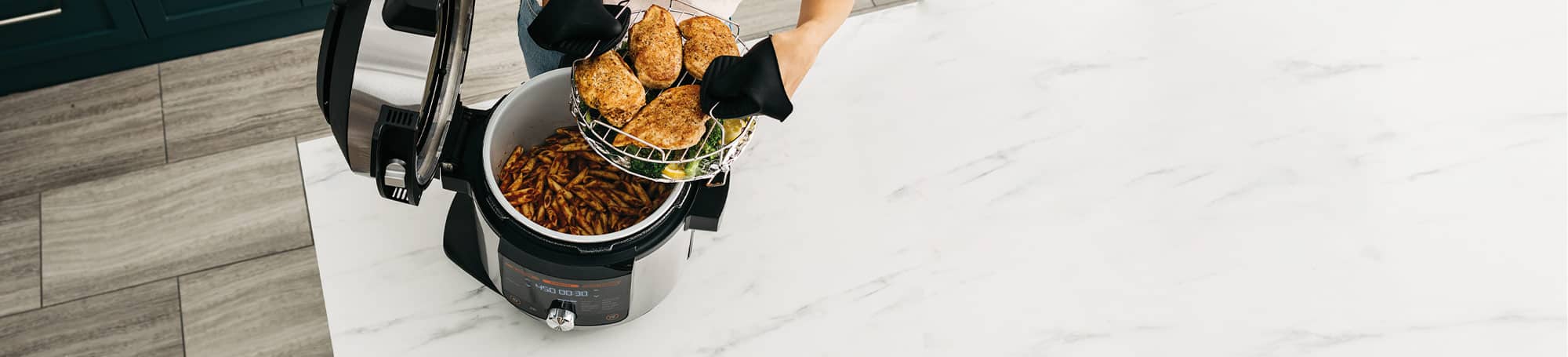 Person holding food on a rack above pressure cooker