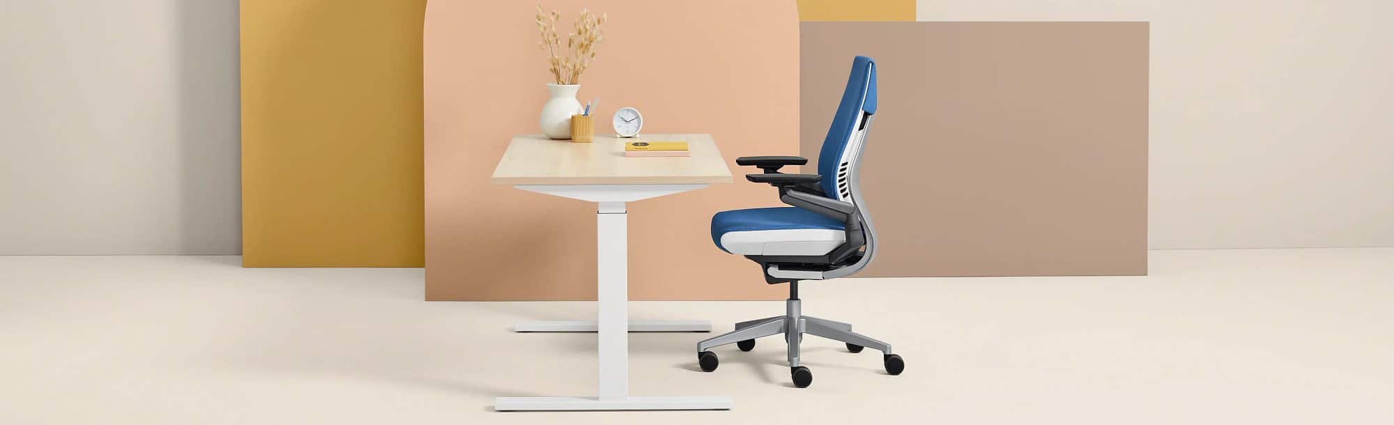 Side view of light-colored standing desk in lower position with blue chair