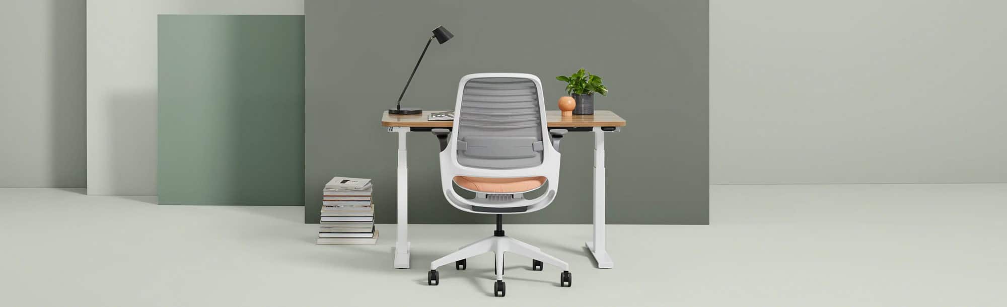 Back view of light-colored standing desk in lower position with white, gray and peach chair