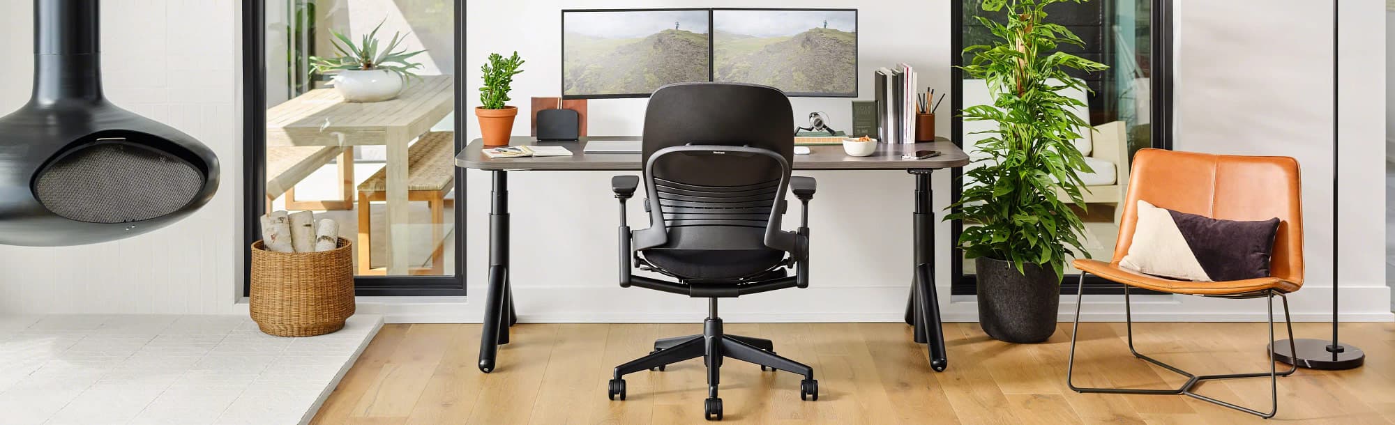 Back view of dark-colored standing desk in lower position in living area with black office chair 