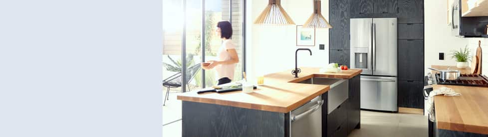 Sunny kitchen with black wall panels and island with built-in stainless steel appliances