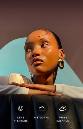A person with their head turned to the side, bright light shines on them from opposite direction, their hands overlapped on a flat surface in front of them at shoulder height, three photo controls: Lens Aperture, Histogram, and White Balance