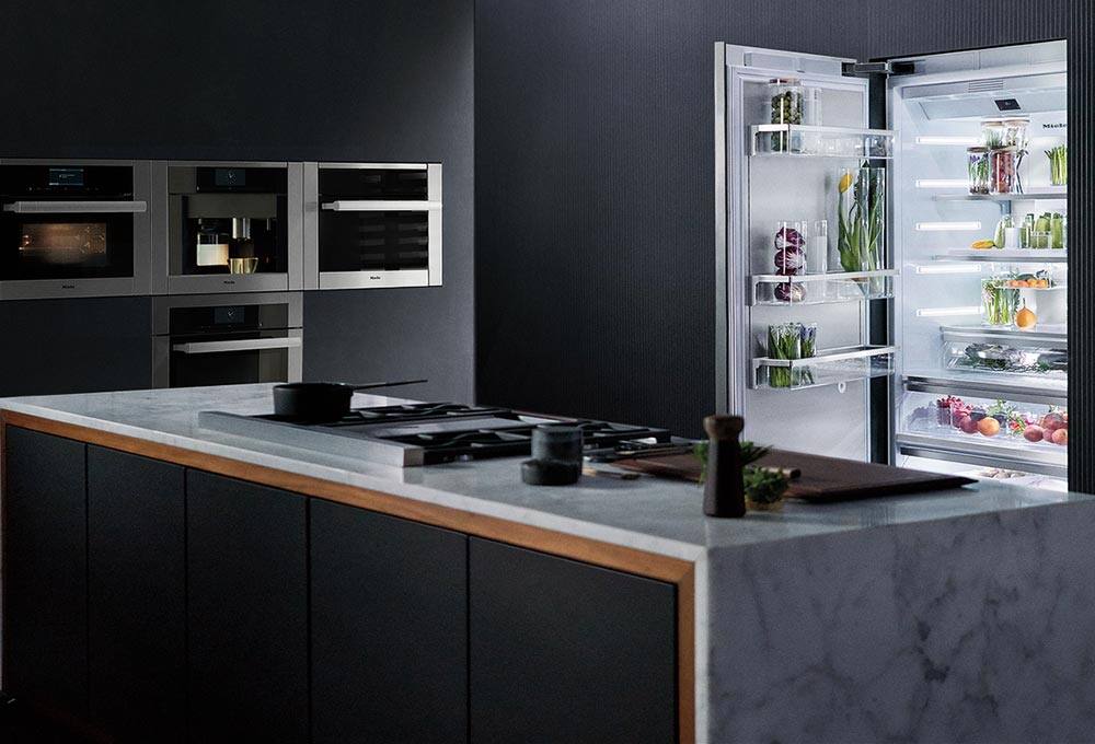 Dark gray kitchen with built-in appliances, cooktop on island, open fridge
