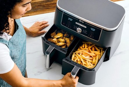 Person cooking french fries and chicken wings in air fryer