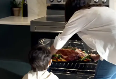 Person taking large pan of food out of oven