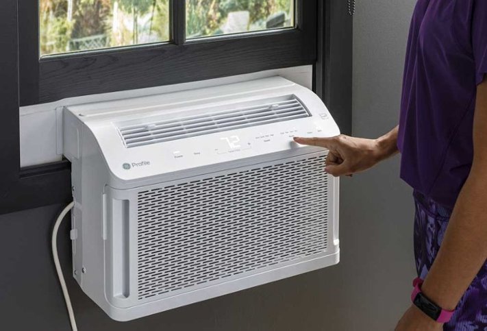 Person adjusting temperature of window air conditioning unit
