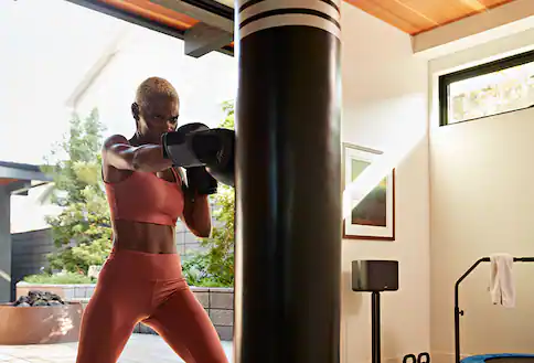 Woman kickboxing with speaker nearby