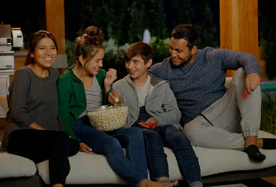 Family on a couch in outdoor space and eating popcorn