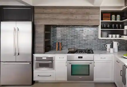 Stainless steel refrigerator, range and wall oven in kitchen with white countertops and cupboards