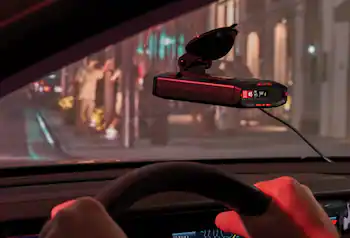 Radar detector attached to windshield with a busy city street in background