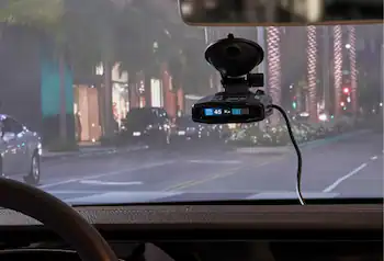 Radar detector attached to windshield in a car driving at night