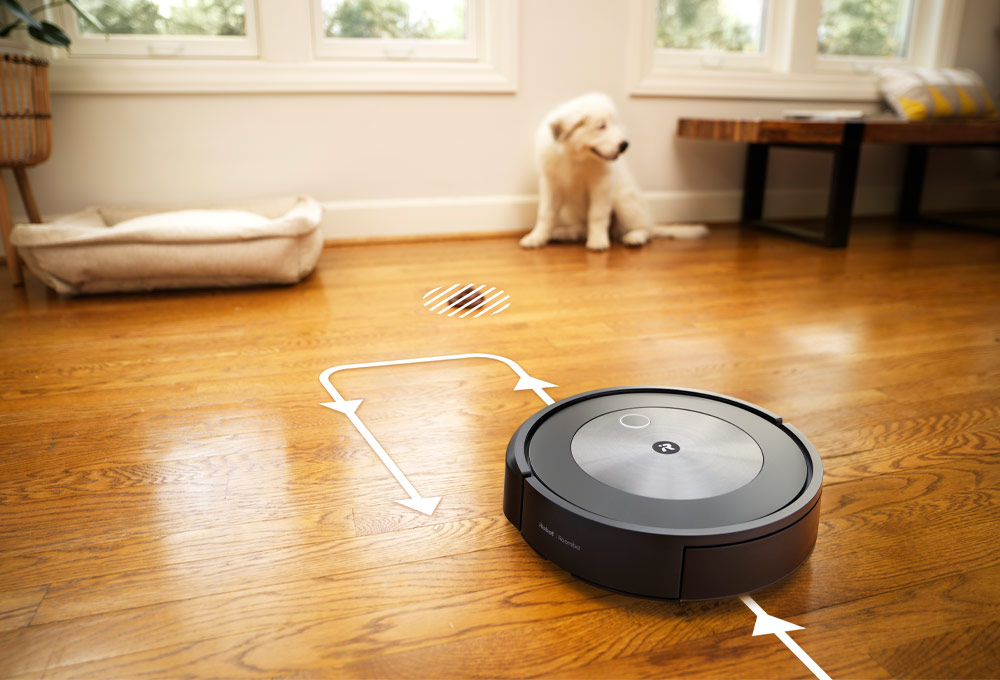 Robot vacuum moving on floor next to dog