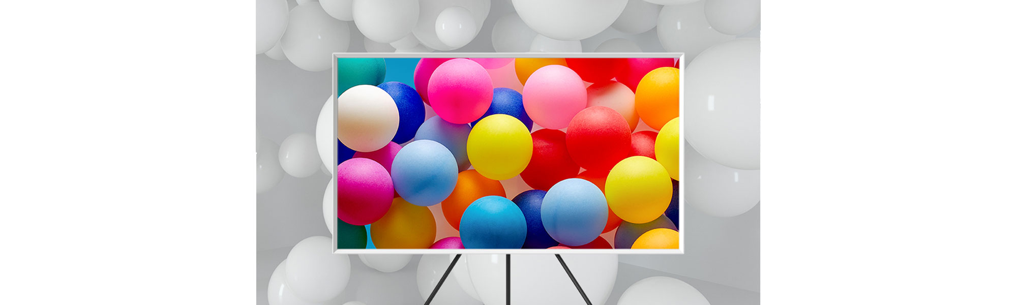 TV with colorful balloons on the screen, and white balloons behind the TV