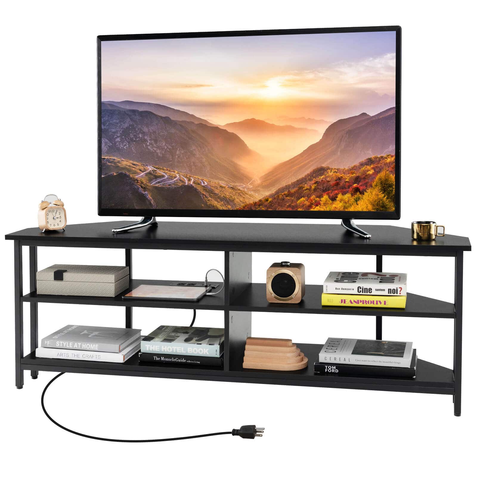 The image features a flat screen TV placed on a black stand. The TV stand has a shelf underneath it, which holds various items such as books, a remote, and a clock. There are also some decorative items like a vase and a bottle on the stand. The TV is turned on, displaying a beautiful sunset scene. The overall setting appears to be a cozy and comfortable living space.