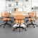 The image shows a conference room with a large wooden table surrounded by orange chairs. The table is set up for a meeting, with several books and a vase placed on it. There are also a few books scattered around the room. The chairs are arranged around the table, with some chairs placed closer to the table and others further away. The room appears to be well-organized and ready for a meeting or discussion.