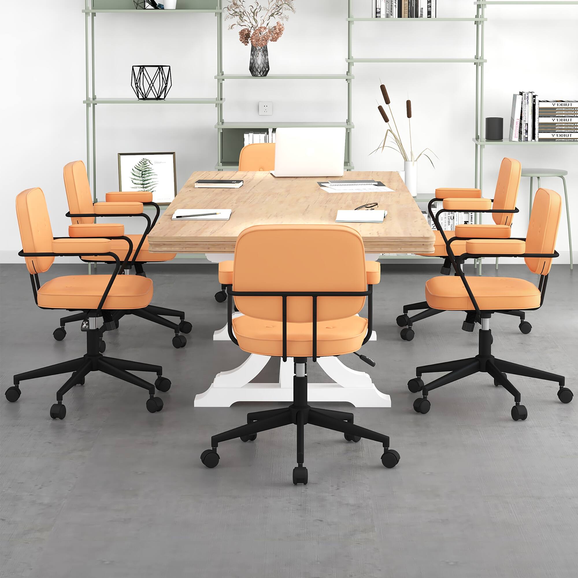 The image shows a conference room with a large wooden table surrounded by orange chairs. The table is set up for a meeting, with several books and a vase placed on it. There are also a few books scattered around the room. The chairs are arranged around the table, with some chairs placed closer to the table and others further away. The room appears to be well-organized and ready for a meeting or discussion.