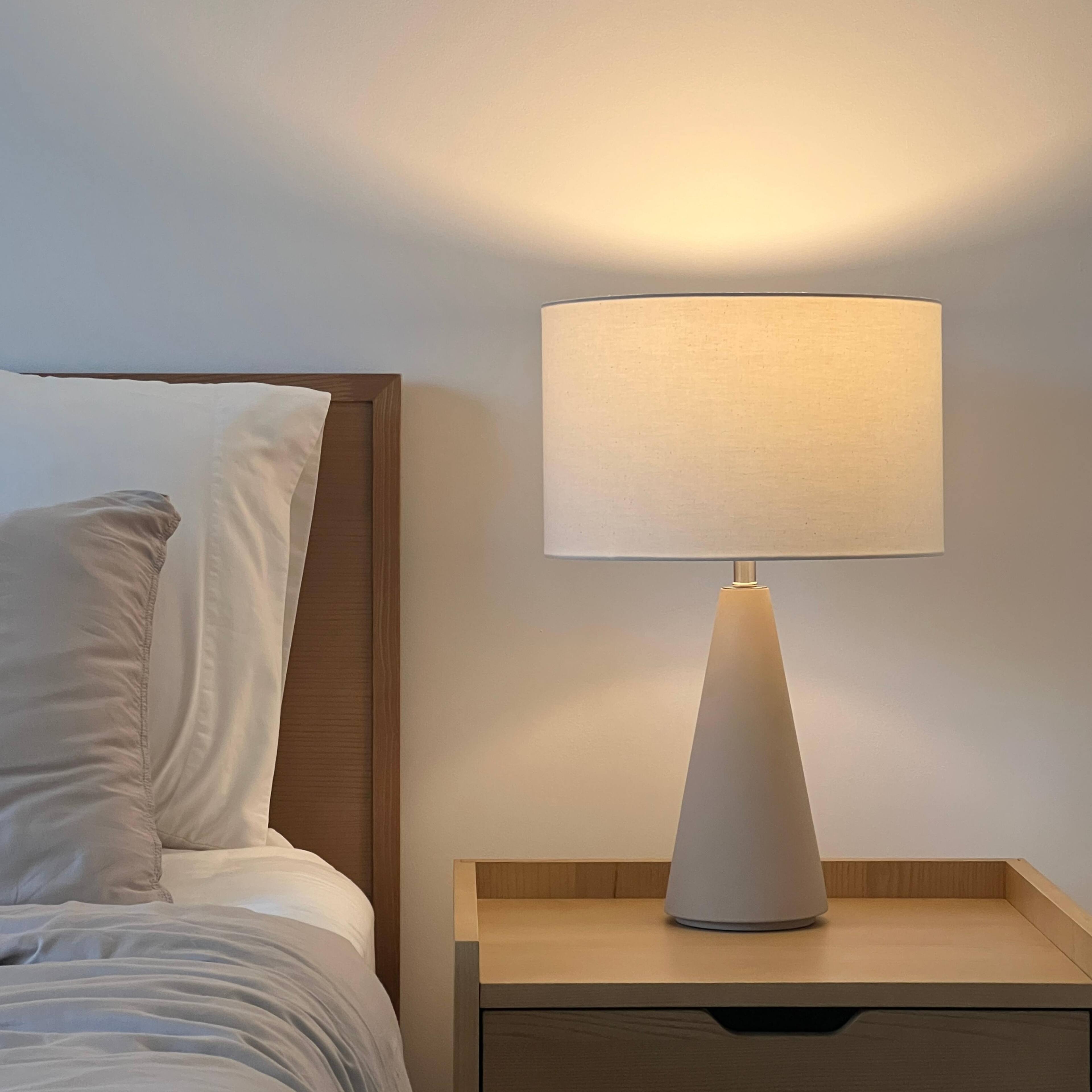 Angle. Brightech - Nathaniel LED Midcentury Modern Empire Bedside Nightstand Desk Lamp with Off-White Cream Fabric Drum Shade - Off-White Cream Cement.