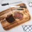 * A wooden cutting board with a piece of meat on it.
* A knife and a pair of tongs on the cutting board.
* A salt shaker on the table.