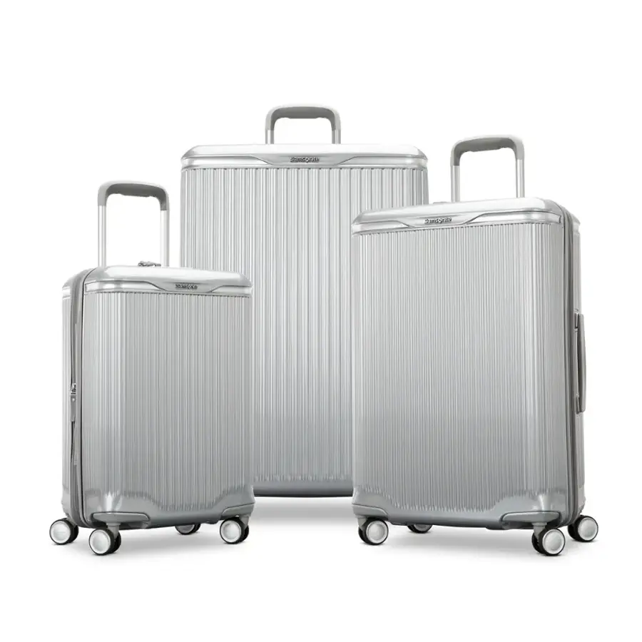 The text on the image reads "SMESAA Sardoal a." However, it is not clear what this text represents or refers to. The image features three silver suitcases, each with a handle and wheels, lined up next to each other.