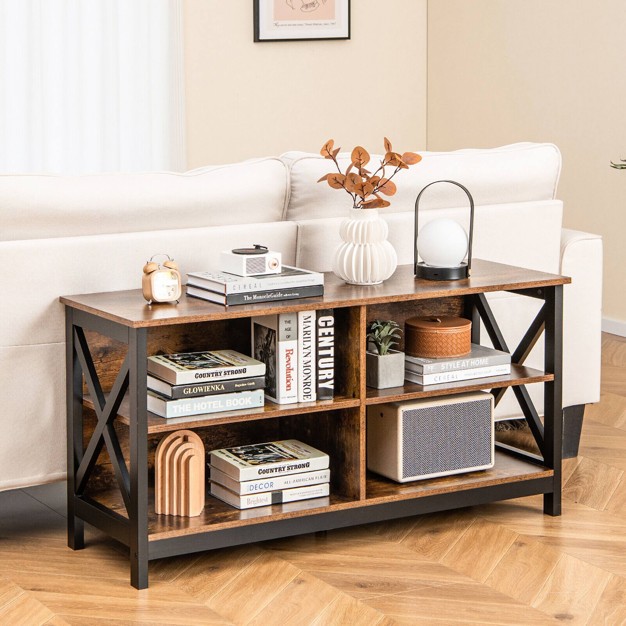 The image features a white couch with a wooden coffee table in front of it. The coffee table is adorned with a variety of items, including several books, a vase with flowers, and a lamp. The books are arranged in different positions, with some stacked vertically and others horizontally. The overall scene appears to be a cozy and inviting living space.