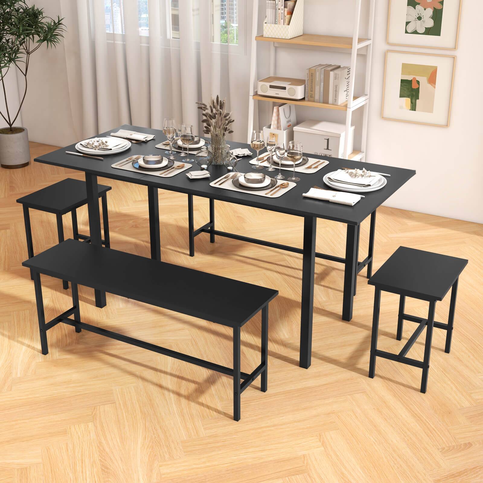 The image features a dining table surrounded by four chairs, all of which are black. The table is set with a variety of items, including wine glasses, cups, bowls, and a vase. There are also several books placed on a shelf nearby. The table is positioned in a room with hardwood floors, and a potted plant is located in the corner of the room.