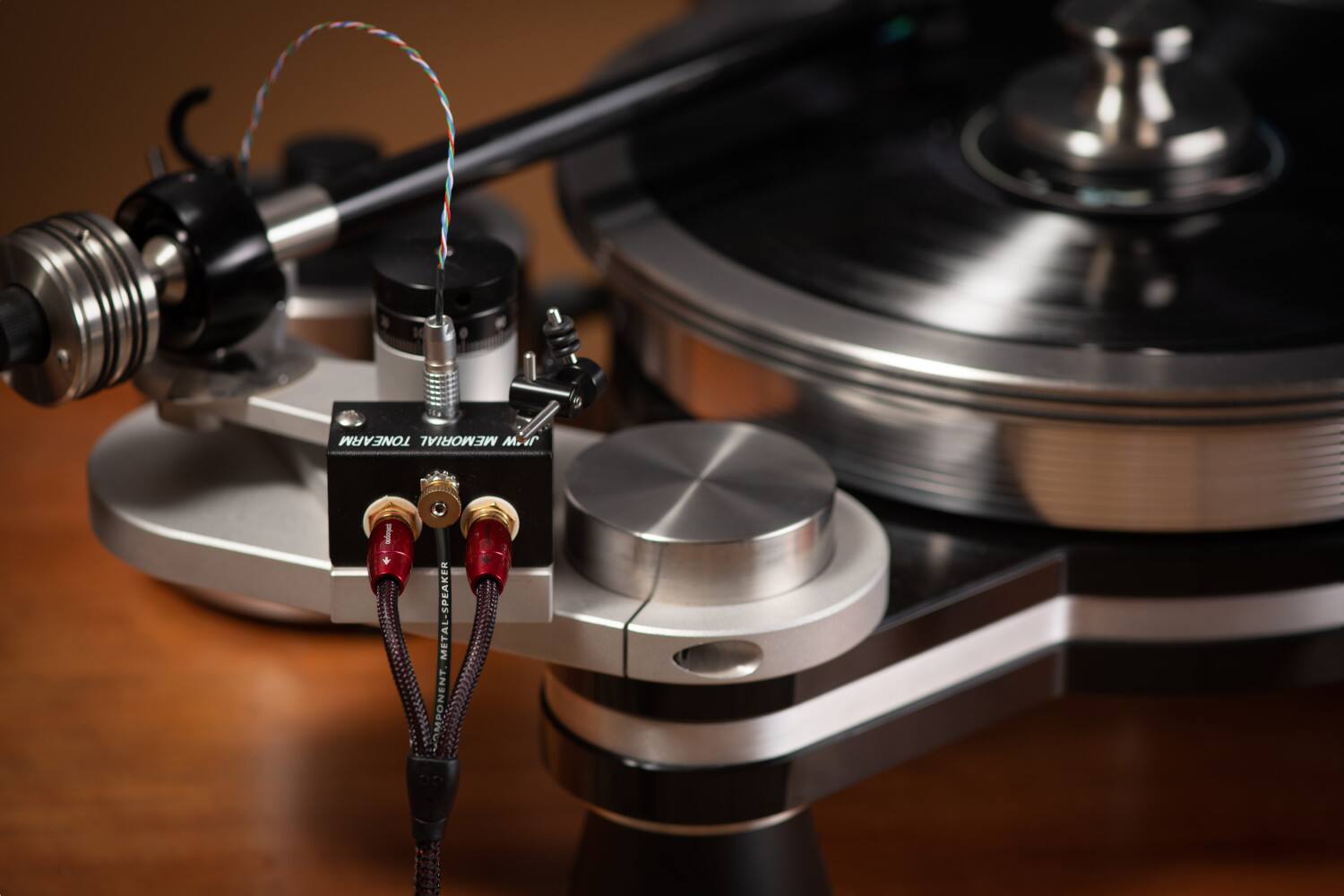 The image features a record player with a tonearm and a metal speaker. The tonearm is connected to a metal-speaker amplifier, which is designed to enhance the sound quality of the record player. The amplifier is placed on a wooden table, and the record player is ready to play.