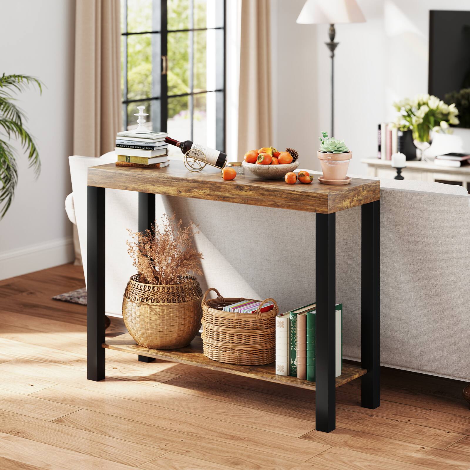 The image does not contain any text. It shows a neatly arranged side table with books, a wine bottle, a bowl of fruit, a small plant, and decorative items.