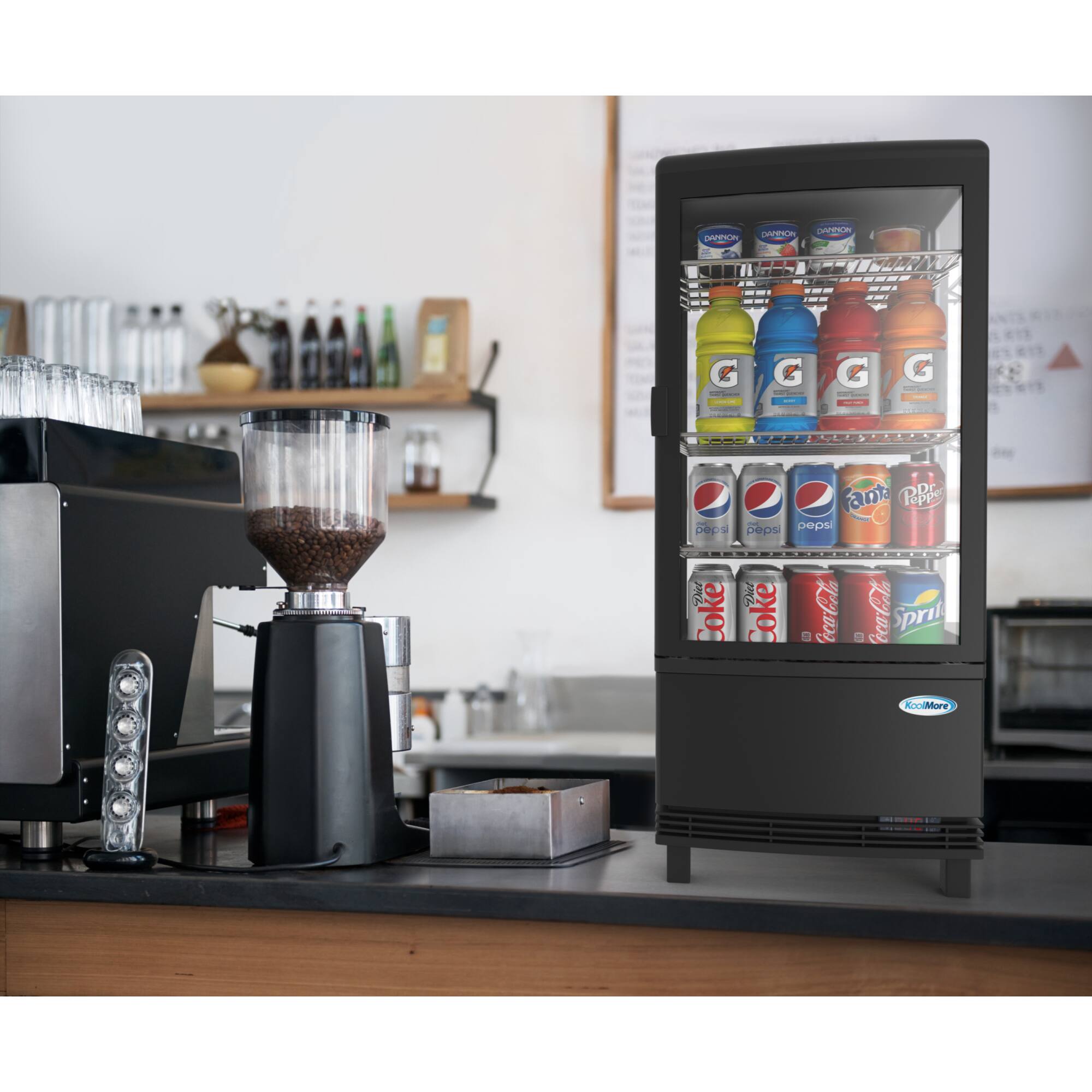 The image features a black refrigerator filled with various drinks, including sodas and juices. The drinks are arranged in a display case, showcasing a wide selection of beverages. Some of the drinks are placed on the top shelf, while others are on the bottom shelf. The refrigerator is located in a kitchen setting, with a counter nearby. The drinks are organized in a visually appealing manner, making it easy for customers to choose their preferred beverage.