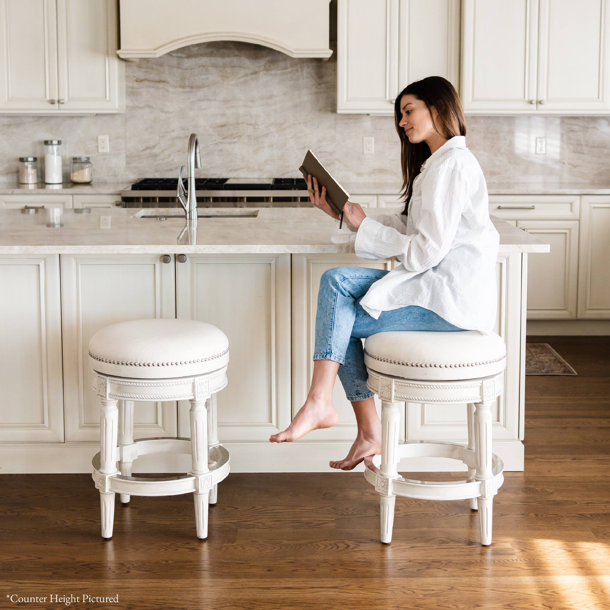 A woman is sitting on a "Counter Height Pictured" stool in a kitchen.