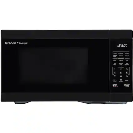 The image features a black Sharp Carousel microwave oven with a timer set at 12:30. The microwave is sitting on a countertop, and its display shows that it is currently set to defrost. The microwave has a variety of buttons on its front panel, including a stop button, a clear button, and a start button. The buttons are arranged in a row, making it easy for users to operate the microwave.