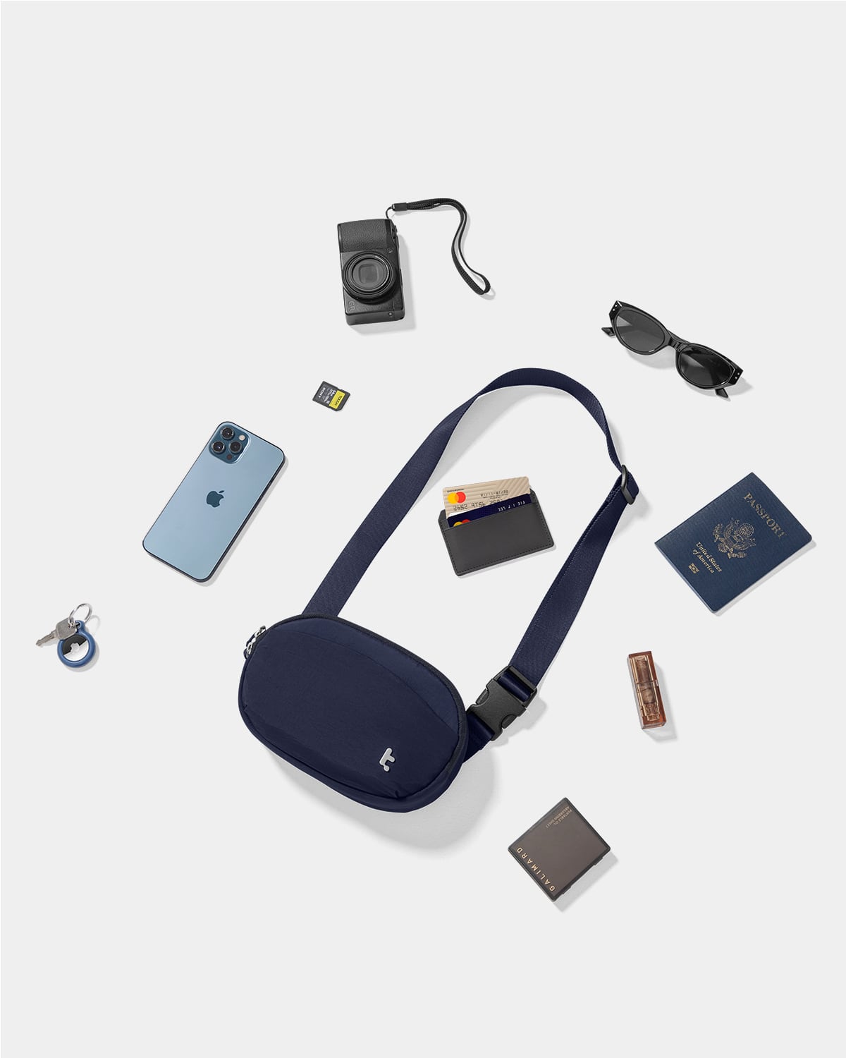 The image shows a variety of items, including a blue bag, a cell phone, a camera, a wallet, a passport, sunglasses, and a keychain. These items are placed on a white background, creating a visually appealing display. The presence of a passport suggests that the person might be preparing for a trip or has recently returned from one. The combination of personal belongings and travel documents indicates that the person values organization and preparedness for their journeys.