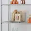 The image features a shelf with various food items and bottles. There are two bottles on the shelf, one located towards the left side and the other towards the right side. Additionally, there are two bowls, one placed near the left bottle and the other near the right bottle. The shelf also contains a variety of food items, including a bag of pasta, a bag of rice, and a bag of nuts. The food items are placed in the middle of the shelf, with the bag of rice slightly to the left and the bag of nuts slightly to the right. The bag of pasta is positioned in the middle, with the bowls placed above and below it.