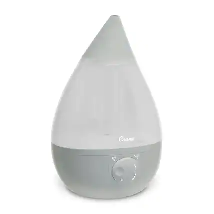The image features a Crane device that is turned off. The device is a white, cylindrical object with a clear glass top. It appears to be a humidifier or an air purifier, designed to improve indoor air quality and provide a comfortable environment. The Crane device is currently not in use, as it is turned off.