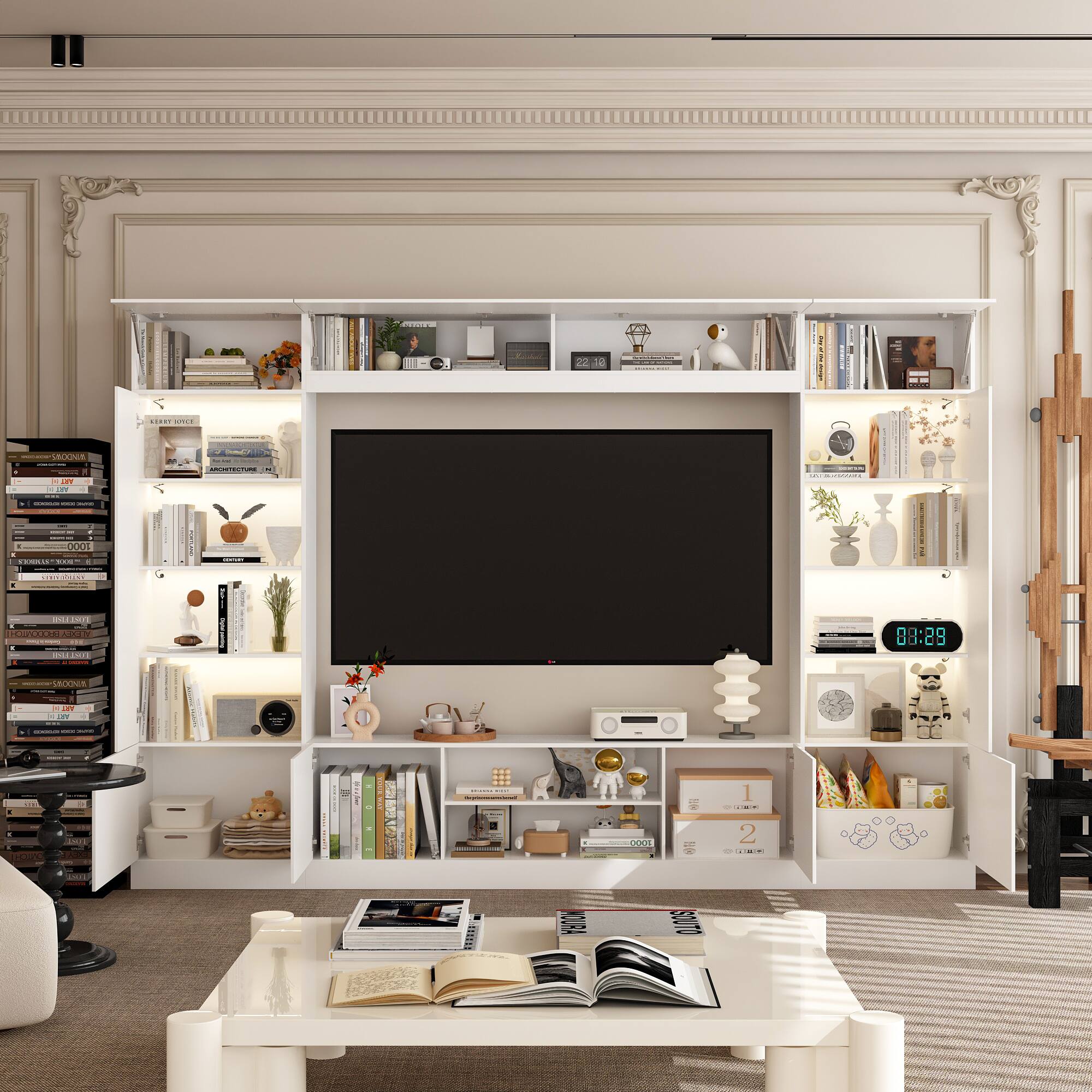 The image shows a living room with a large flat screen TV mounted on the wall. The room is furnished with a couch, a coffee table, and a bookshelf filled with books. There are also several decorative items in the room, such as a clock, a vase, and a potted plant. The room appears to be well-organized and comfortable, with a cozy atmosphere.