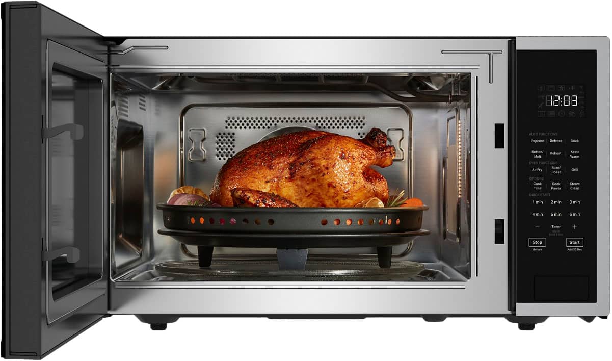 The image shows a microwave oven with a chicken inside, cooking on the defrost function. The oven has various options, including cook time, power, steam, clean, and quick start. The timer can be set for 1, 2, 3, 4, or 5 minutes, and the oven also has a quick start function. The microwave is a black and silver appliance that is currently set to defrost the chicken.