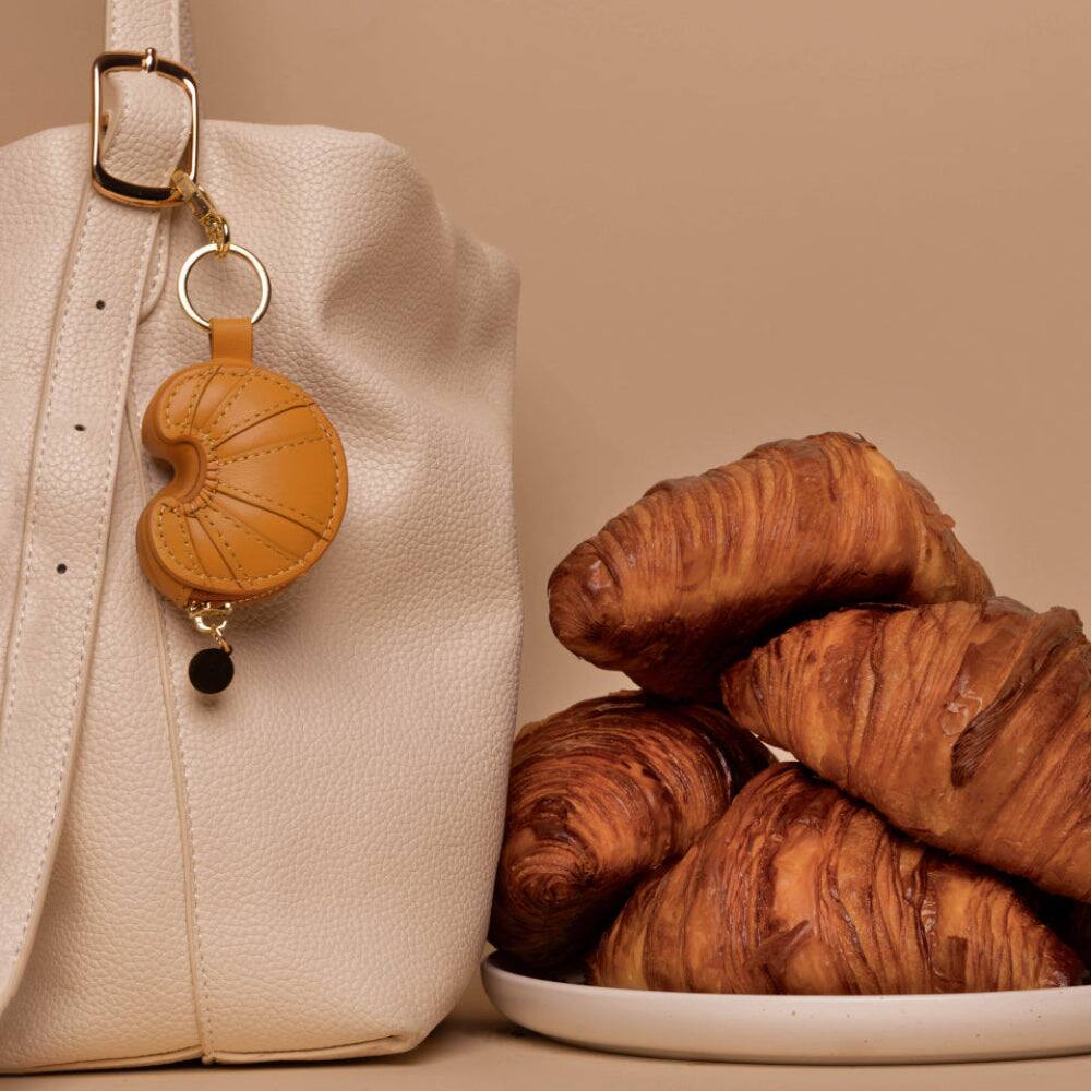 Left. Posh Tech - Croissant Leather Bag Charm for Airtag® - Brown.